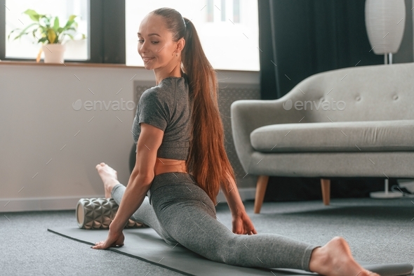 Big stretch for legs. Young woman in yoga clothes doing fitness indoors  Stock Photo by mstandret