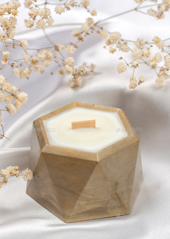 Scented candle with wooden wick in a flowerpot. Soy wax candle on a background of white fabric