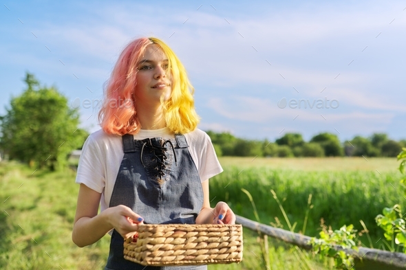 Teenage girl with basket of fresh strawberries walking along country road