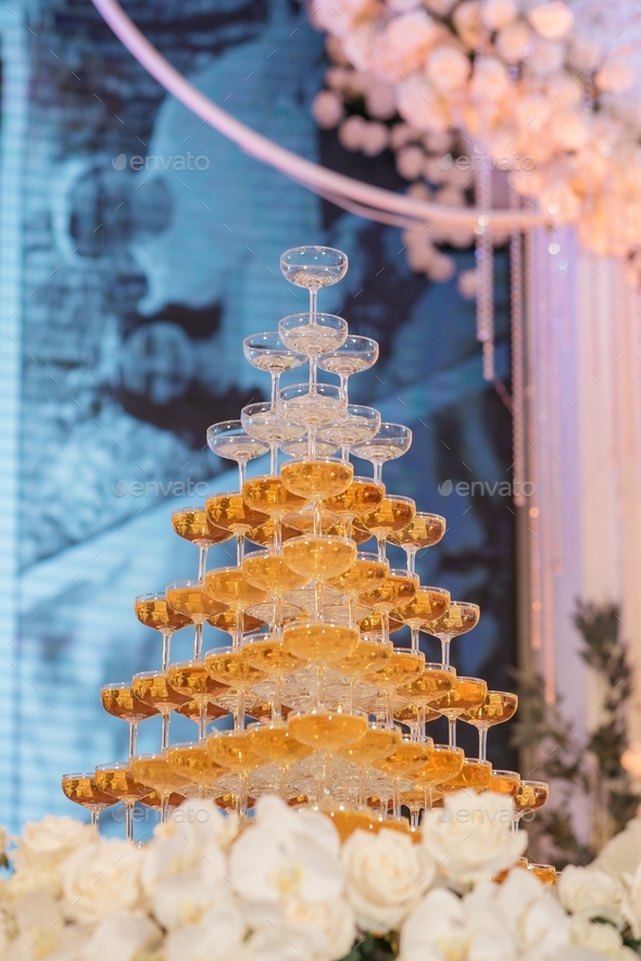 Vertical low angle shot of a champagne tower, glasses filled with champagne alcohol