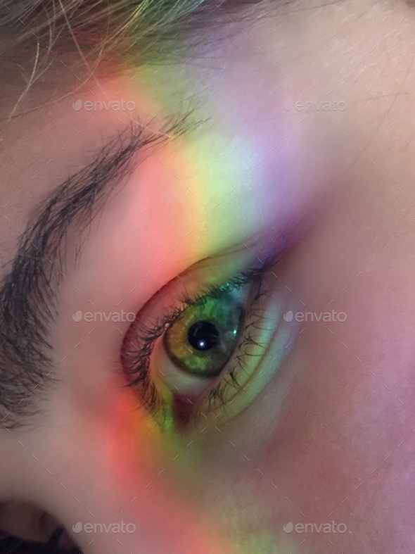 Vertical shot of the real rainbow on a green female eye - seeing the world in color concept