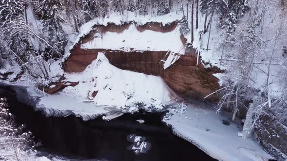 Aerial view of Brasla river cliff. Krauklkalna iezis. The drone flies over a small forest river.