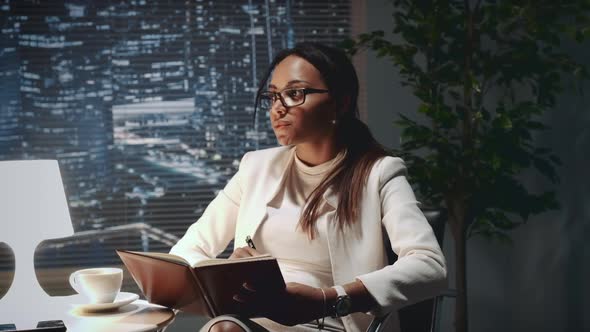 Mixed Race Business Girl Making Notes in Her Notebook at the Office alt