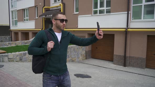 A Male Blogger Walks Down the Street and Writes Content.