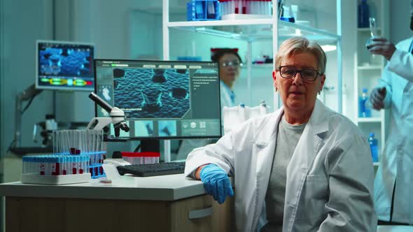 Portrait of Old Chemist Woman with Fatigued Face in Front of Camera alt