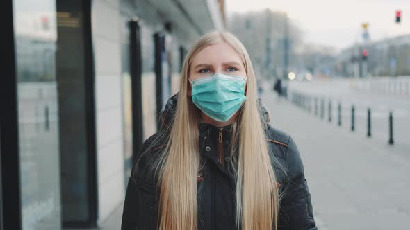 Young Blonde Woman Wearing a Protective Medical Mask on the Street alt