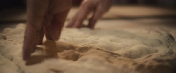 Chef preparing traditional pizza al taglio dough with his hands, slowly kneading dough. alt