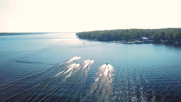 Gorgeous 4K aerial shot of jet skis speeding along a lake on a beautiful sunny day. alt