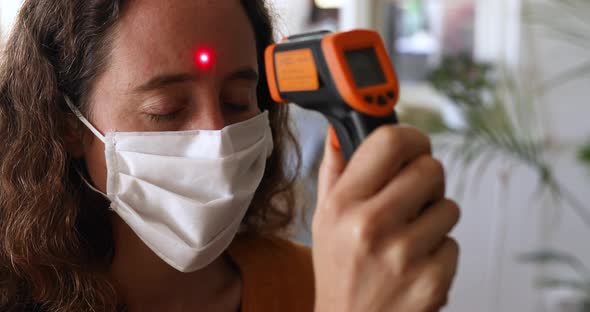 Caucasian woman taking her temperature at home alt