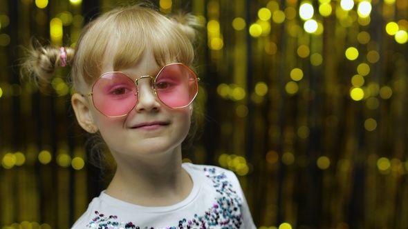 Child Kid Dancing, Claping Her Hands, Fooling Around. Girl Posing on Background with Foil Curtain alt