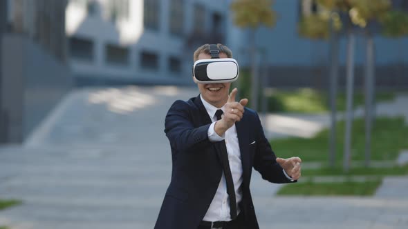 Happy Businessman Playing a Game on Imaginary Screen Using Augmented Reality Goggles alt
