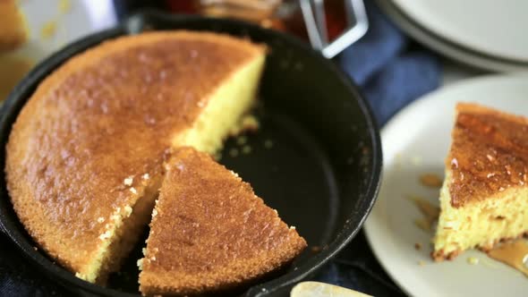 Slice of sweet cornbread with honey on the plate. alt