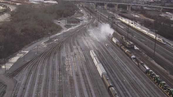 Train yard with switching rail tracks as a train speed towards the city alt