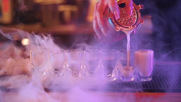 bartender filling up shot glasses with alcoholic drinks (slow motion) alt
