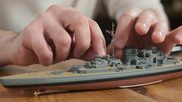 Happy adult male assembler plastic model of warship according to instructions