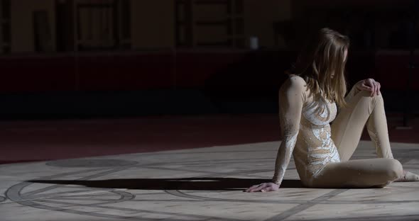 Blonde Young Woman Is Sitting on the Ground After the Training Circus alt