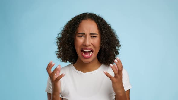 Portrait Of Emotional Black Female Shouting Over Blue Studio Background alt