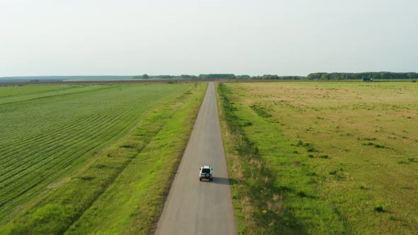 Aerial View of a Car Driving on a Country Road alt