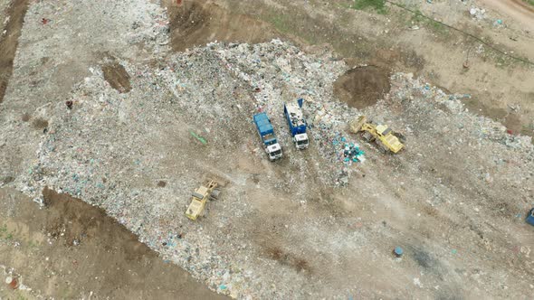 Top View on Garbage Trucks Unload Garbage to a Landfill alt