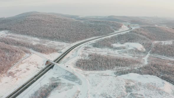 Drone Approach To the Road with Traffic Among the Hills in Winter alt