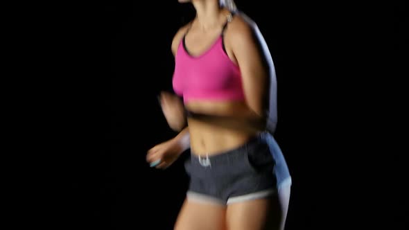 Girl Sporty in Shorts with Pockets Running on a Black Background. Close Up alt