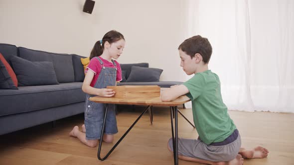 Boy and girl playing a wooden table game at the living room together alt