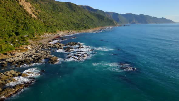 Beautiful wild rocky Kaikoura coastline with tall mountains and coastal road in New Zealand alt