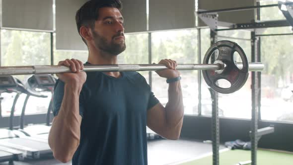 Young athlete caucasian guy exercising doing deadlift a barbell over his head fat burning workout. alt
