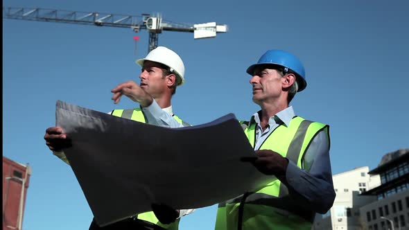 Mature Men Inspecting Blueprints on Construction Site alt