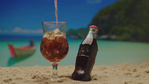 Pouring Coke Drink Into the Glass Full of Ice Cubes Near Coke Bottle Standing on the Sea Shore alt