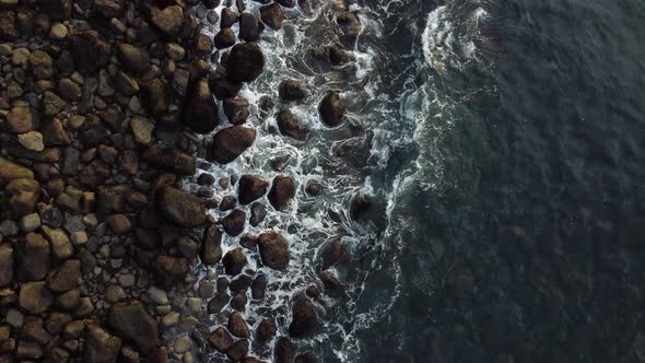 Top View of Waves Breaking Over Rounded Rocks