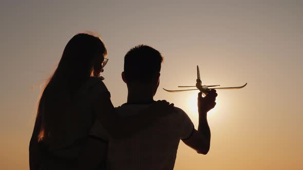 Silhouette of a Man Playing with a Girl with a Toy Plane alt