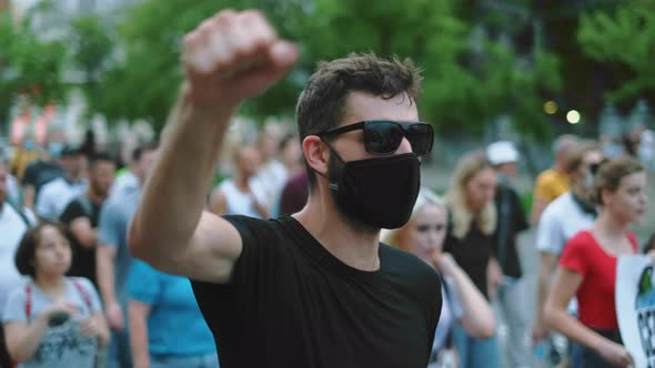 Portrait of Covid Protester in Glasses Facemask with Waving Arm Fist on Rally