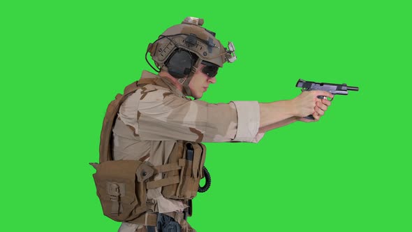A Special Forces Soldier with a Helmet on His Head Walking and Shooting From Hand Gun on a Green alt