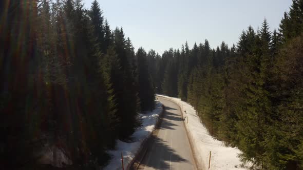 Aerial view of snowy mountain forest with a road