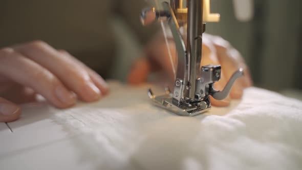 A Female Hand Pushes Material Through a Sewing Machine alt