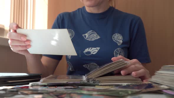 Unrecognizable Woman Looks at Photos From Family Album