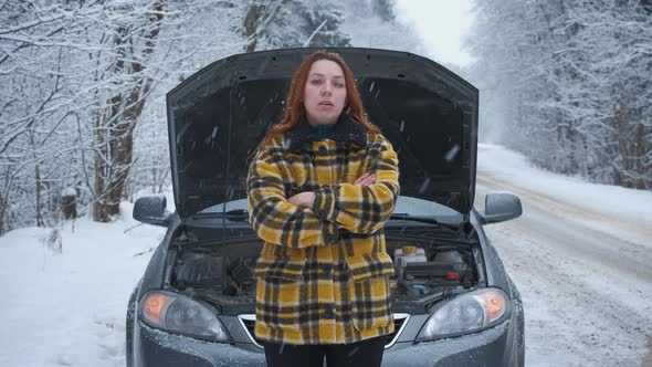 A Young Woman in the Winter Forest Is Standing on the Road with a Broken Car