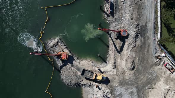 Large construction machinery working on a coastal project to develop a new boating marina and harbor alt