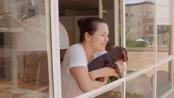 Young Dark Hair Woman Smile and Bring Her Dog to See Out of the Window