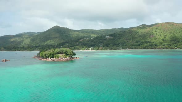 Aerial dolly over emerald bay Cote d'Or toward tiny islet St. Pierre alt