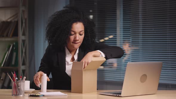 Portrait of African American Woman Taking Out Samples of Cosmetics From a Cardboard Box alt