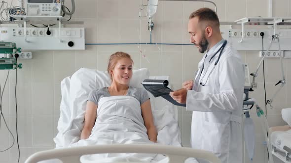 Male Doctor Talking to Female Patient in Hospital Bed alt