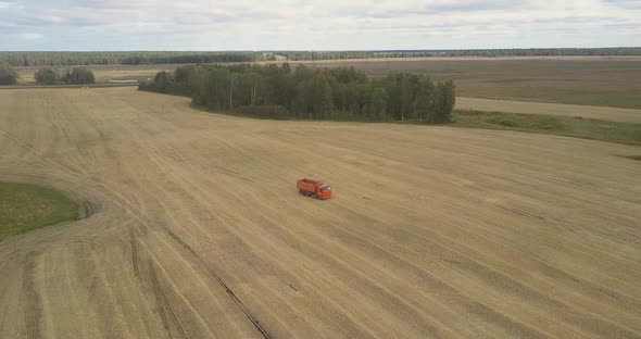 Bird Eye View Truck Drives Along Harvested Field To Thresher alt