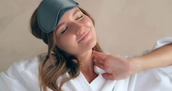 Happy Woman in Bathrobe Puts on Blindfold Sitting on Bed
