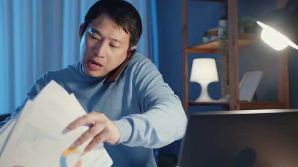 Young Asia businessman use smartphone call meeting agenda assignment paperwork with at laptop. alt