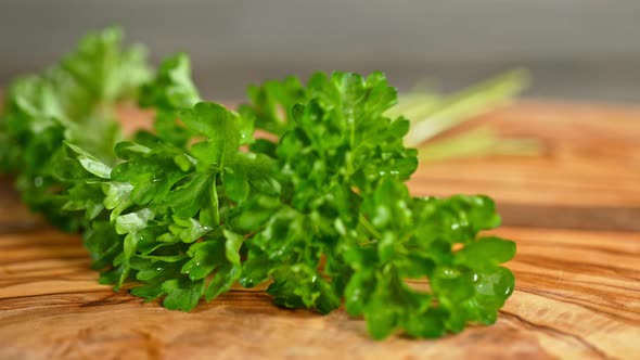 Super Slow Motion Shot of Fresh Parsley Falling on Wooden Cutting Board at 1000Fps alt