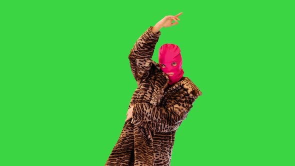 Active Girl in Pink Balaclava Performs Energetic Dance on a Green Screen Chroma Key