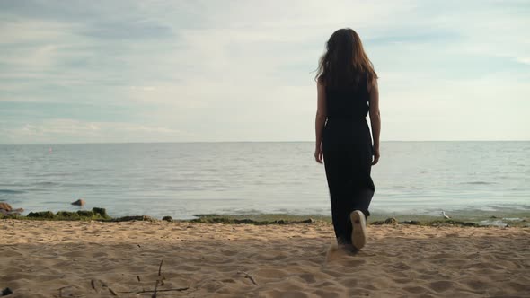 Handheld Shot of Woman Back on a Sandy Beach Coming To River