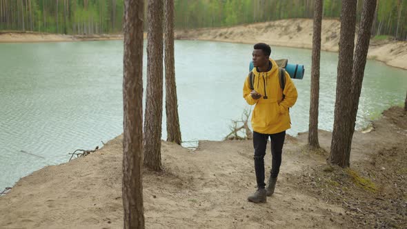 A Black Man is Walking on Top of a Mountain and Typing a Message and Photo on His Smartphone alt